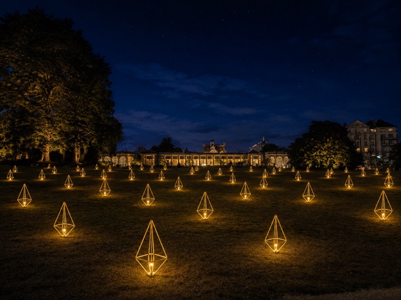 Des lanternes géométriques dorées alignées dans l’herbe devant l’orangerie du Thabor